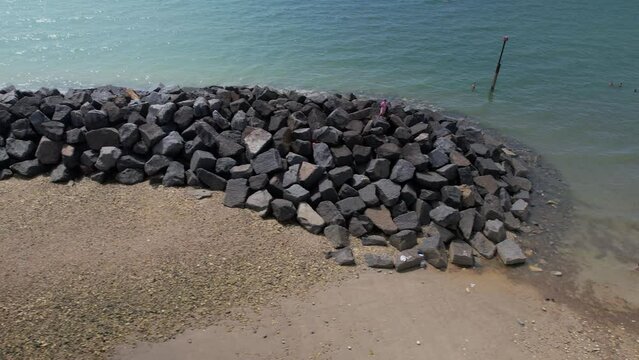 Water Breaker Rocks To Protect Coastline Erosion At Elmer Sands Beach In West Sussex, UK - aerial sideways