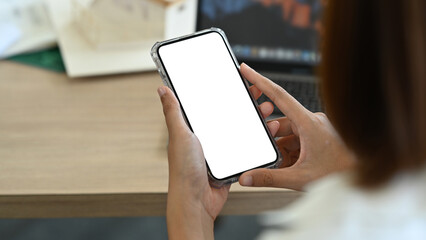 Close up view of female worker using mobile phone at her workplace. White empty screen for your advertise design