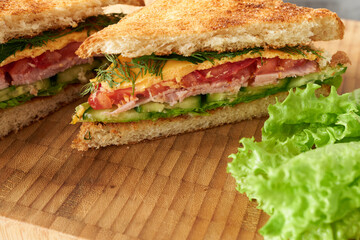 Close-up of sandwiches in section on wooden background with lettuce leaves.