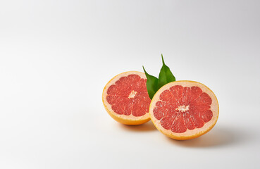 Grapefruit halves with green leaves on white background with space for text.