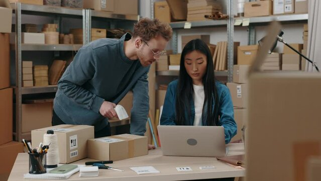 Inventory managers scans cardboard box with barcode scanner in the warehouse, and preparing cardboard parcels ready for shipment. Post workers. Small business concept.