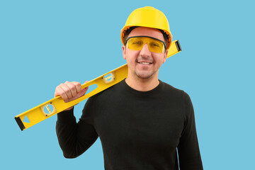 Young builder or worker in a helmet on a blue background. Construction concept