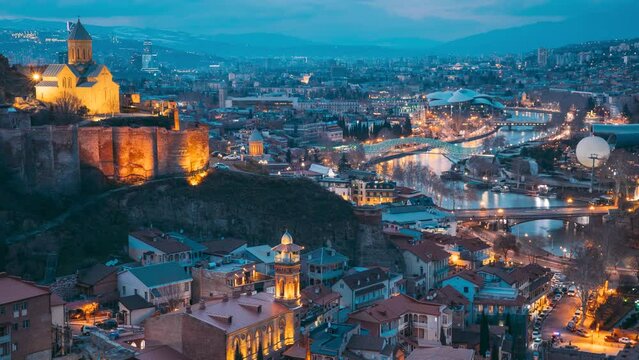 Tbilisi, Georgia. Day To Night timelapse Transition. Elevated Top View Of Famous Landmarks In Night Illuminations. Georgian Capital Skyline Cityscape. City During Sunset And Night Illuminations. Day