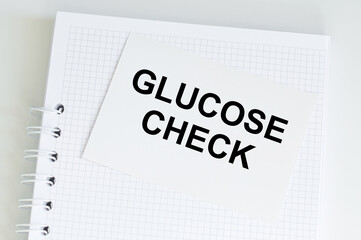 Glucose check inscription on a card on the background of a notebook on the table, a medical concept