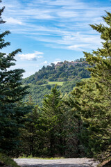 a small in village on top of a hill surrounded by green trees and a blue sky in the background