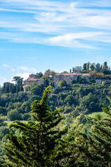 a small in village on top of a hill surrounded by green trees and a blue sky in the background