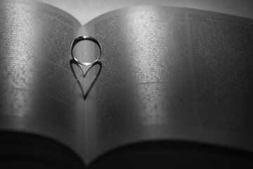 Ring auf Buch wirft Schatten wie Herz