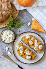 Open sandwiches whole grain bread with spice pumpkin and feta cheese on a stone table. Healthy food, vegetarian appetizer. View from above.