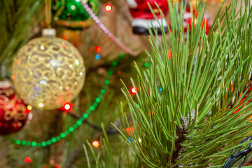 Spruce branch with Christmas balls and festive lights on the background.