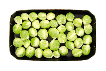 Fresh Brussels sprouts, in a black cardboard punnet, from above, isolated over white. Green leaf...