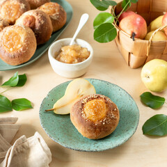 Delicious homemade buns with jam and fresh pears on a wooden background. Mini pies. Cooking recipe.