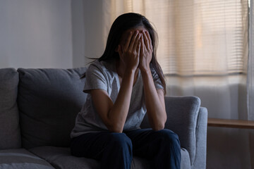 Mental health, depressed sad asian young woman, girl sitting on sofa, couch, expression to face difficulty, failure and exhausted. Thoughtful worried suffering depression feeling lonely, alone at home
