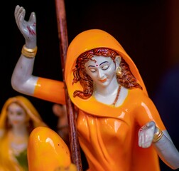 Closeup of a colorful statue of the Mirabai in an orange dress.
