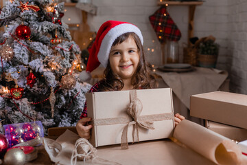 a happy little girl at home in the kitchen is packing Christmas presents in crab boxes. new year's sale