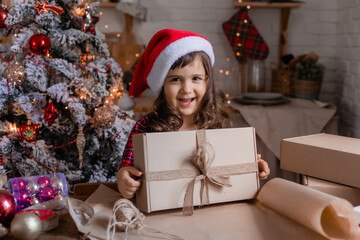 a happy little girl at home in the kitchen is packing Christmas presents in crab boxes. new year's sale