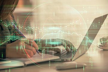Double exposure of businesswoman hands typing on computer and forex graph hologram drawing. Financial analysis concept.