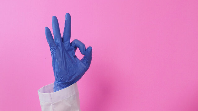 The A-Ok Hand Sign and doctor wear violet  latex glove on  pink background.