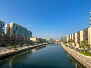 Fototapeten The canal and buildings in the Al Raha Beach neighbourhood in Abu Dhabi. Al Raha Beach is a mixed-use development with waterfront apartments. © Hein van Tonder