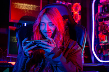 Asian woman live stream she play video game via smartphone at home neon lights living room, Gamer...