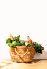 Front view of shopping straw bag full of fresh leafy vegetables. Healthy food ingredients shopping concept.