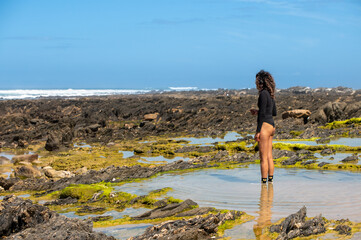 Woman seen standing in water and watching the ocean
