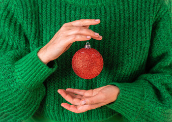 Female in green sweater are holding the symbol of the New Year in their hands - a red Christmas...
