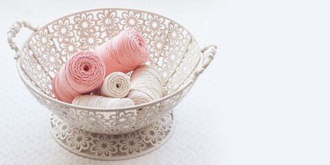 Handmade macrame braiding and cotton threads in basket on white background. Good image for macrame and handicrafts banners and advertisement. Copy space