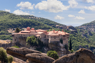 Fototapeta na wymiar Red tiled roofs, chimneys and ornamented arched windows of religious medieval buildings of The Holy St Varlaam Monastery in Meteora, Greece