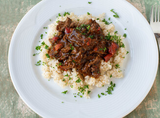 Beef ragout with brown rice on a plate. Cooked with low fat and high protein meat - natural...