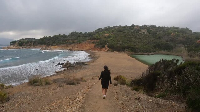 Ragazza solitaria nella tempesta sulla spiaggia tra mare e lago