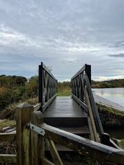 Obraz premium Wooden bridge crossing over a lake in the countryside. Taken in Bury Lancashire England. 