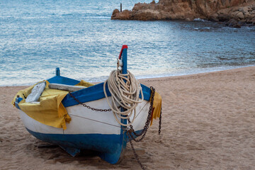 Solitaria barquita de pesca amarrada en la fina arena de la orilla en playa de Blanes con el...