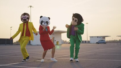 Cinematic video of a couple wearing elegant suits and funny animals masks having fun and celebrating outdoor in a a parking lot rooftop