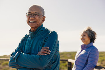 Happy senior man smiling at the camera while standing on a foot bridge