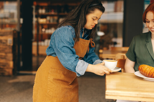 Professional waitress with Down syndrome serving a customer in a cafe