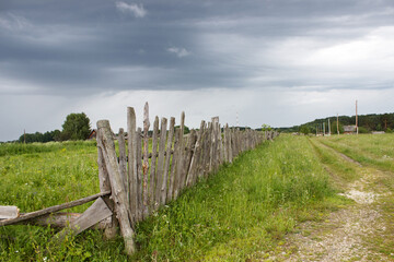 Obraz premium rural landscape with wooden old fence, road and meadow