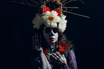 Woman with mexican skull halloween makeup on dark background. Day of the dead aka Dia de Muertos and halloween concept.