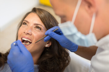 Dentist repairing and checking teeth of a young woman  at the dental clinic