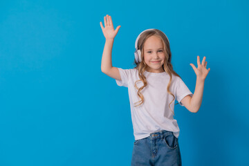 blonde girl in jeans and a white T-shirt listens to music with headphones and dances