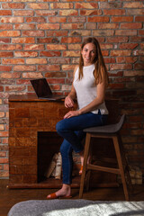 Fototapeta na wymiar Smiling woman sitting on a high chair with a laptop behind her