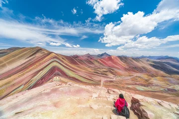 Foto op Plexiglas Vinicunca Vrouwelijke toerist zit op de voorgrond van de Rainbow Mountains op een hoogte van 5000 meter.