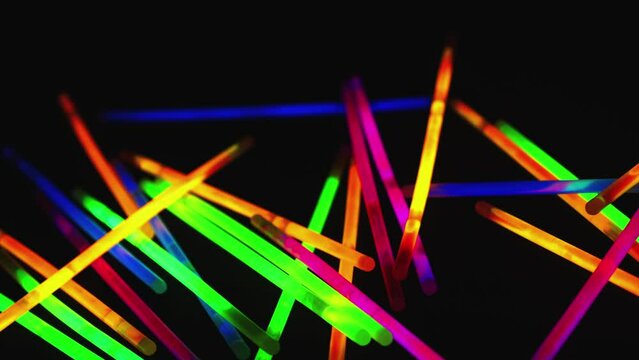 Narrow focus camera moves across colorful glow sticks on dark surface