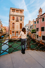 Fototapeta na wymiar Woman from behind looking at a characteristic building on the canals of Venice
