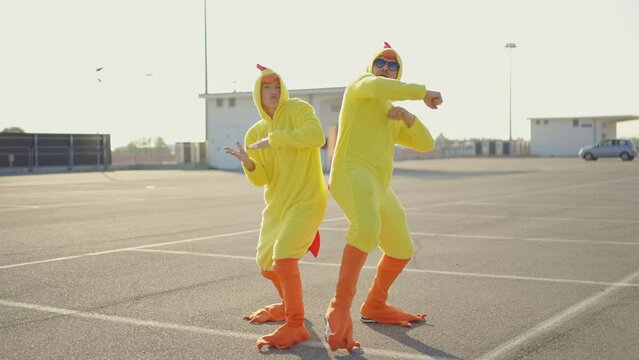 Cinematic video of a couple having fun wearing a chicken pajama costume outdoor. Man and woman celebrating outside. Representation of carefree concept