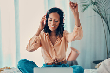 Woman, music and bed with laptop, dancing and headphones in bedroom, relax and smile. Girl, dance and room with streaming, computer and listen on web, internet and app for radio, audio and technology