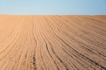 Plowed field after ploughing, on the background is a blue sky