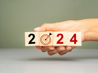 Business planning in 2024. Hand holding of wooden cubes with the letters 2024 on a table with a...