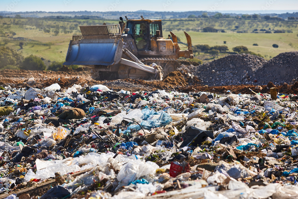 Wall mural Heavy machinery shredding garbage in an open air landfill. Pollution