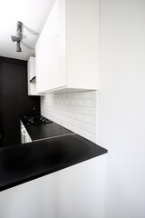 Small  kitchen design with white kitchen cabinets, white kitchen island with lots of storage, black countertops, subway tiles, gas stove.