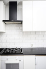 Small  kitchen design with white kitchen cabinets, white kitchen island with lots of storage, black countertops, subway tiles, gas stove.